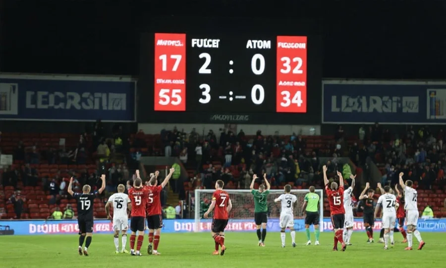 足球比赛结束时，电子记分牌上显示不同比分，球员在球场上庆祝